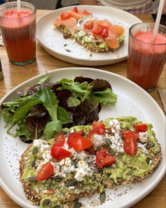 Image contenant un avocado toast avec des tomates cerises accompagné d'une salade verte servi dans une assiette